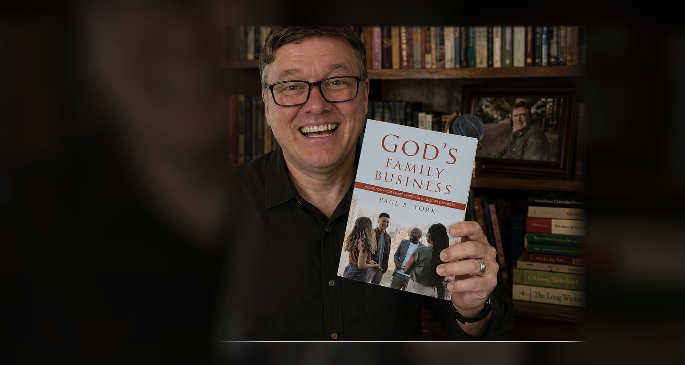 Paul B. York holding his book in his study