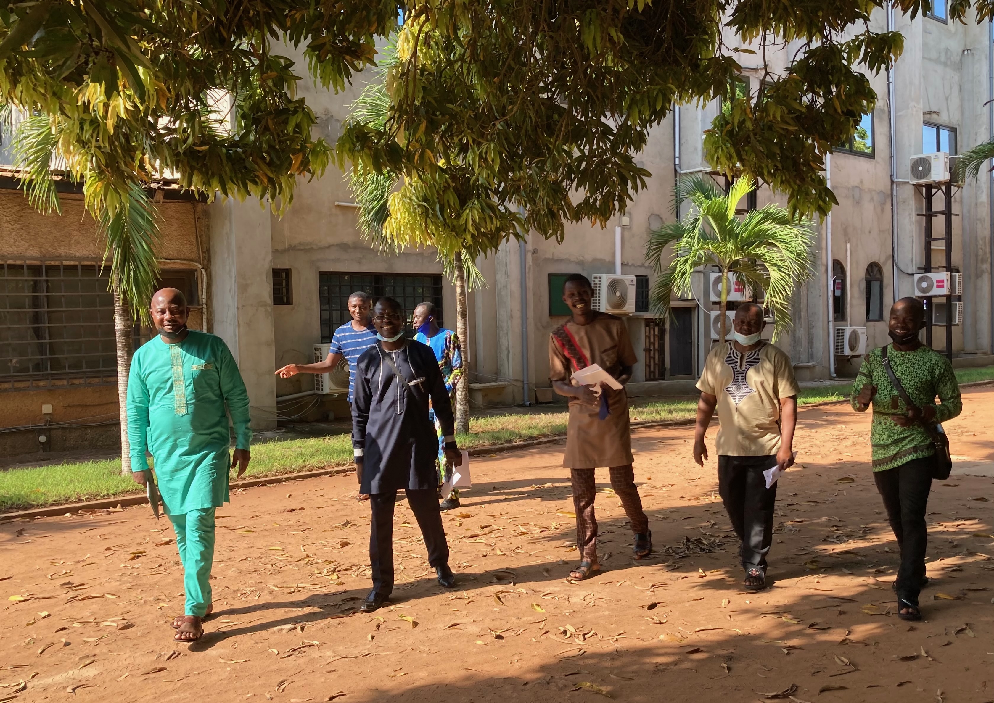 People walking together outdoors under the trees